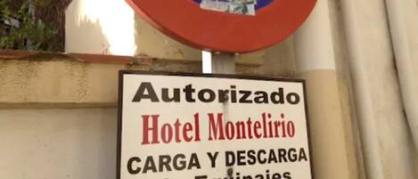 A no parking sign with a hotel name and loading/unloading services sign below it.