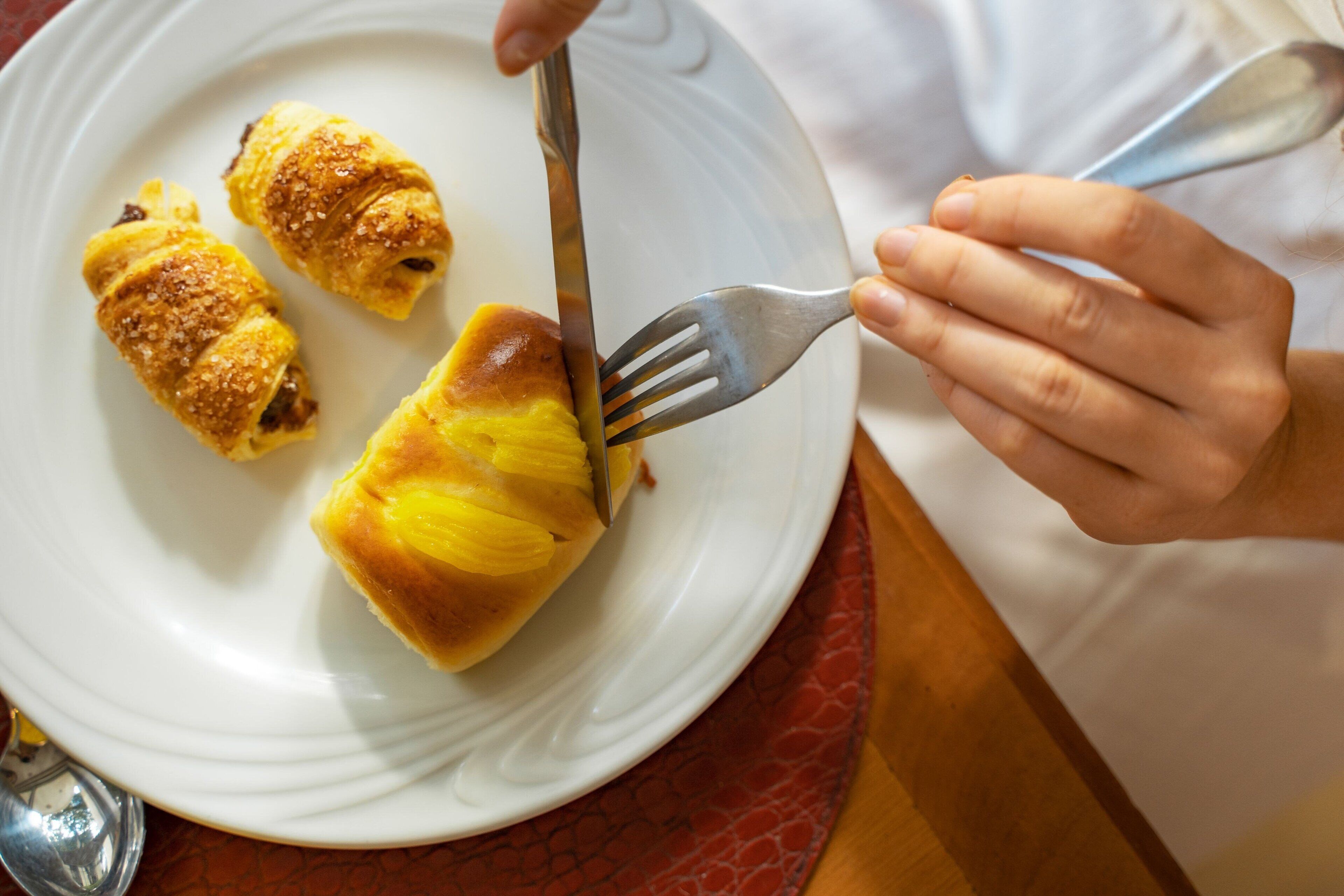 Una persona cortando un pastel sobre un plato blanco.