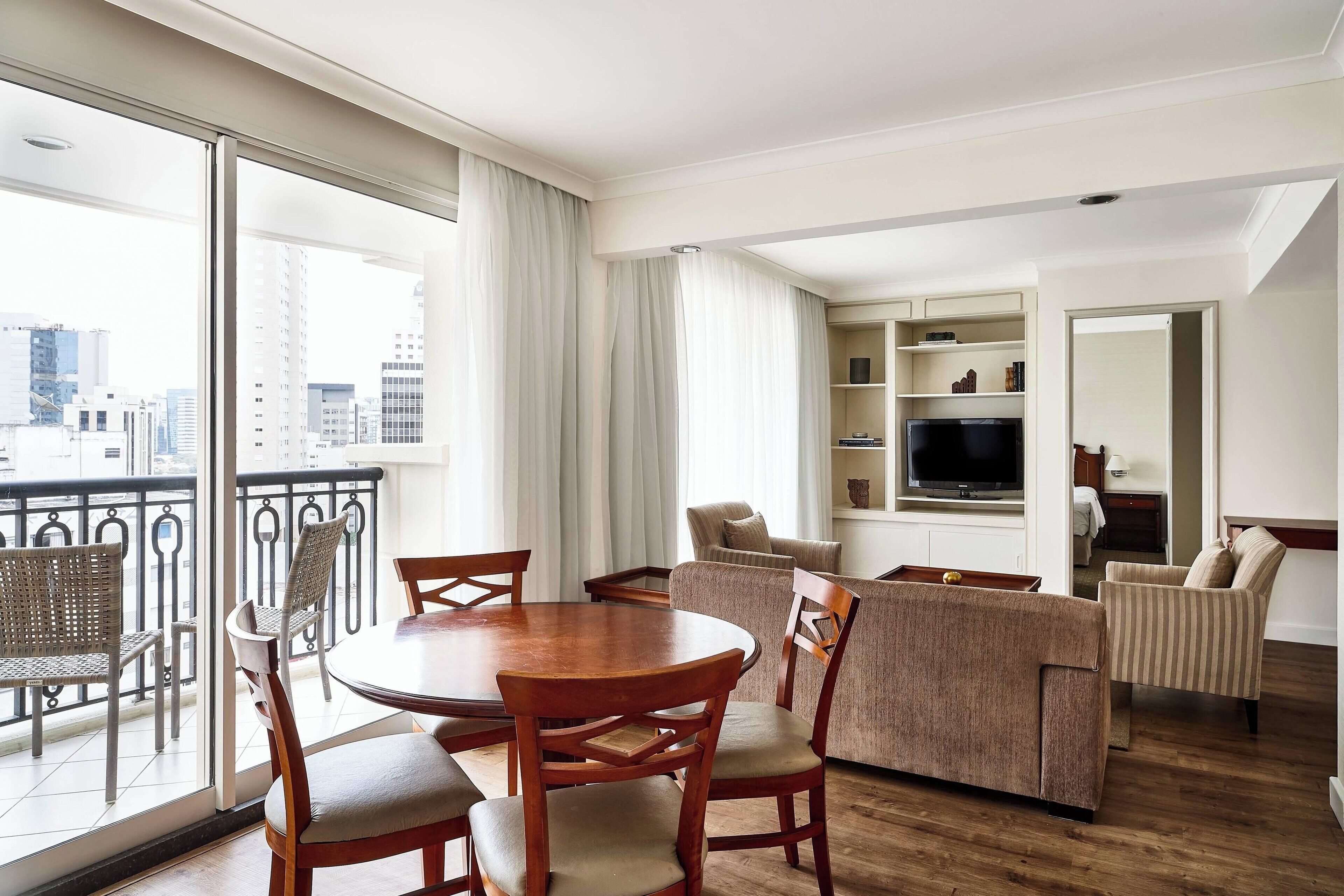 Een moderne woonkamer met een ronde houten tafel en stoelen, een bank en een televisie.