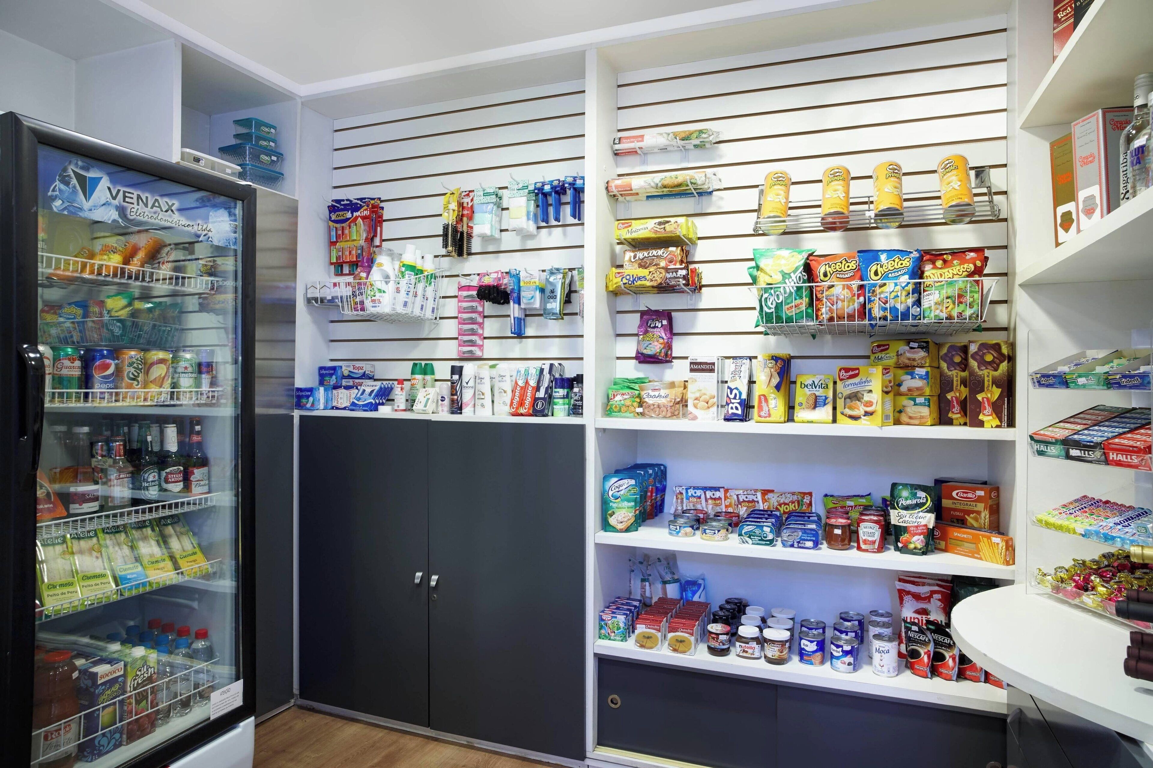 Een overzichtelijke provisievoorraadkast met planken vol snacks, drankjes en huishoudartikelen.