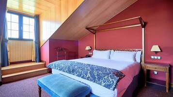 A bedroom with a four-poster bed, a bench, a nightstand, and a window with curtains.