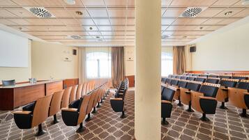 A conference room with rows of chairs, a reception desk, and a patterned carpet.