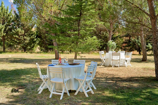 An outdoor dining area with round tables and white chairs, surrounded by trees. - Hotel Sonsoles Ávila (Ávila)