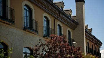 Un edificio con ventanas de arco y balcones, que presenta fachada de piedra y una chimenea.