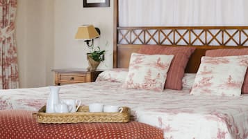 Un dormitorio ordenado con cama, mesita de noche, lámpara y una bandeja con jarra y tazas.