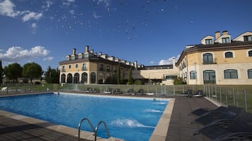 Una piscina con solárium, rodeada de edificios.