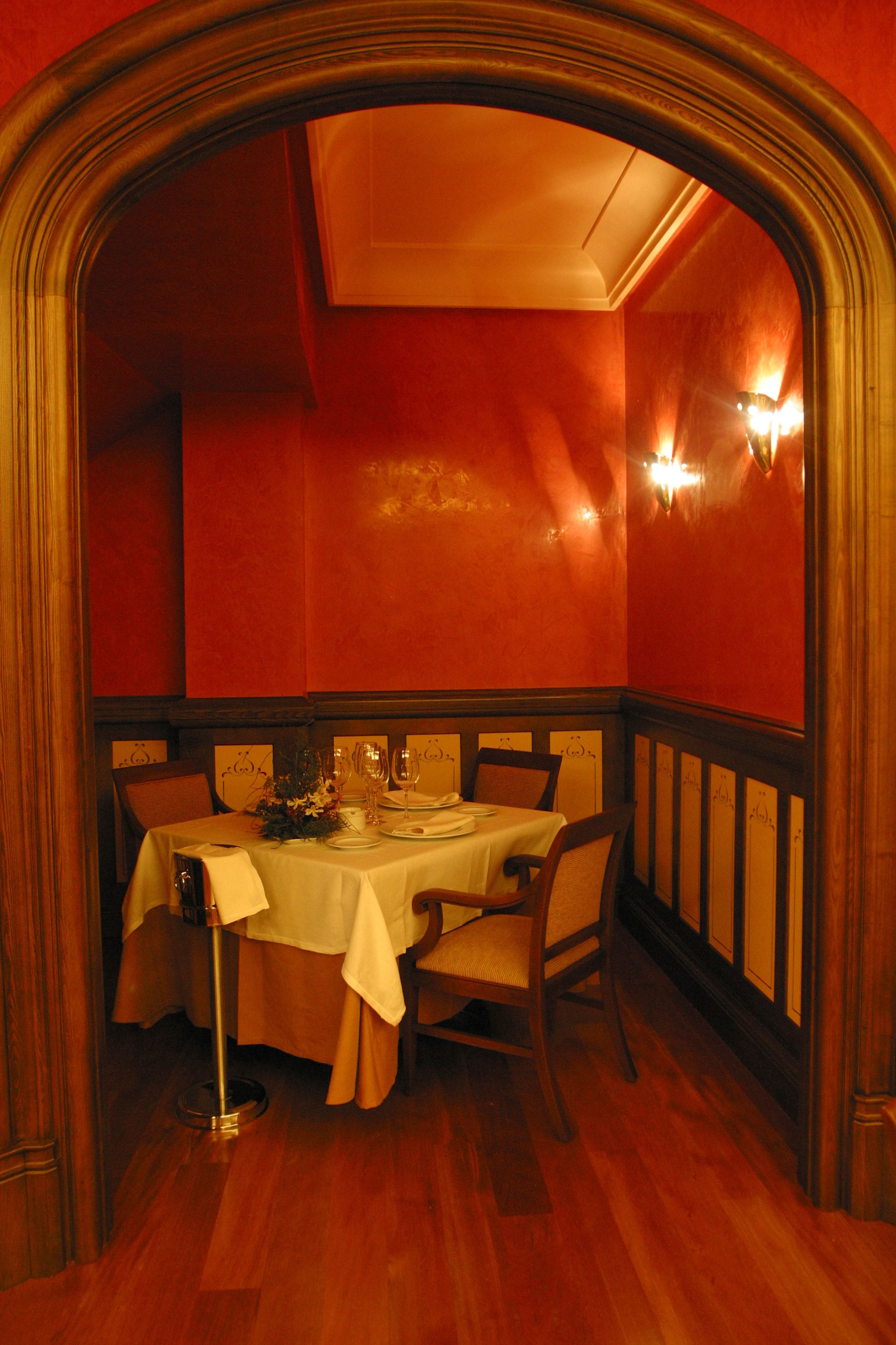 A dining area with a table set for four, surrounded by wooden chairs.