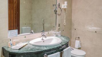 A bathroom with a marble sink, a mirror, a toilet, and a shower area.