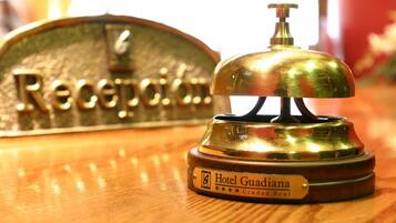 Un comptoir d’accueil d’hôtel avec une cloche en laiton et une enseigne indiquant « Hôtel Guadiana Ciudad Real ».