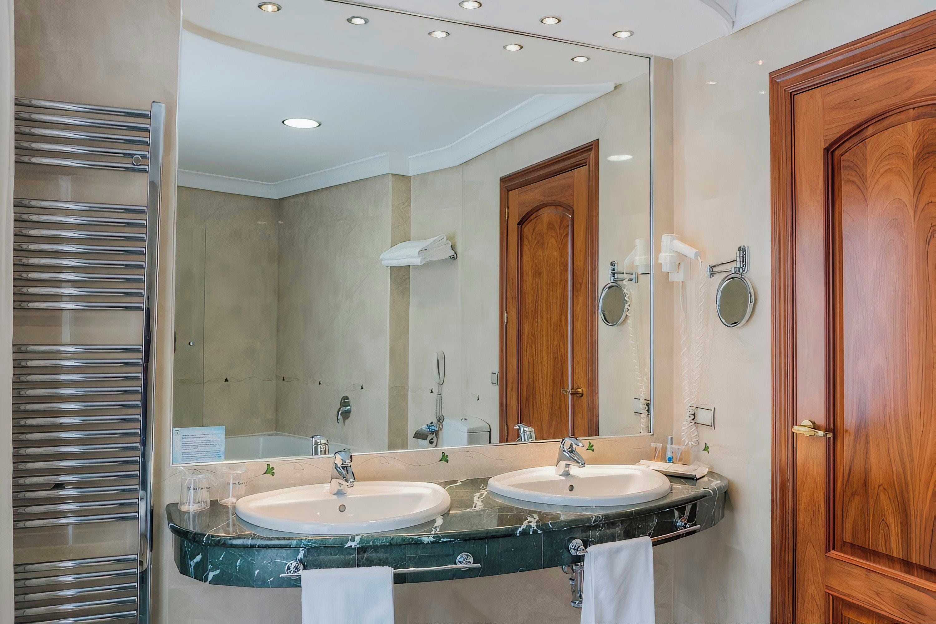 A bathroom with two sinks, a large mirror, and a towel rack.