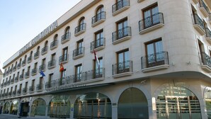 Un hotel de varios pisos con balcones, amplias ventanas en arco y una entrada destacada.