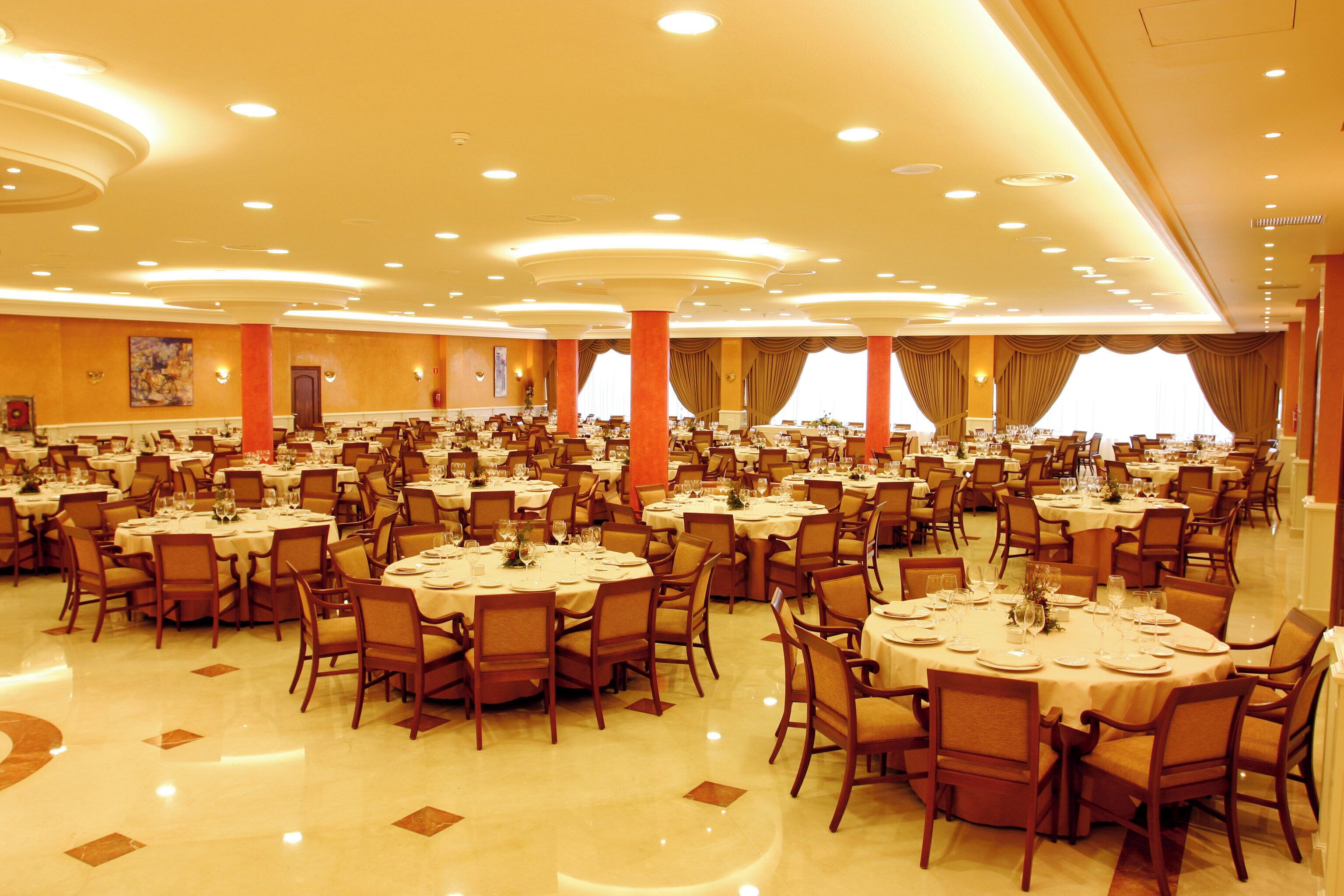 A large banquet hall with multiple round tables and chairs, arranged in rows.