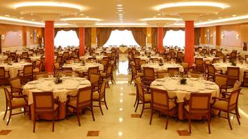 Un amplio salón de banquetes con mesas redondas, sillas y un pasillo central.
