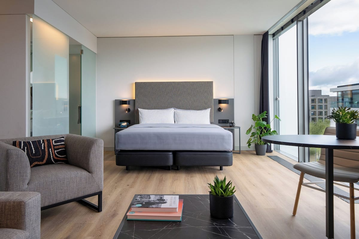 Une chambre d’hôtel moderne dotée d’un grand lit, d’un canapé, d’une table à manger et offrant une vue sur la ville.