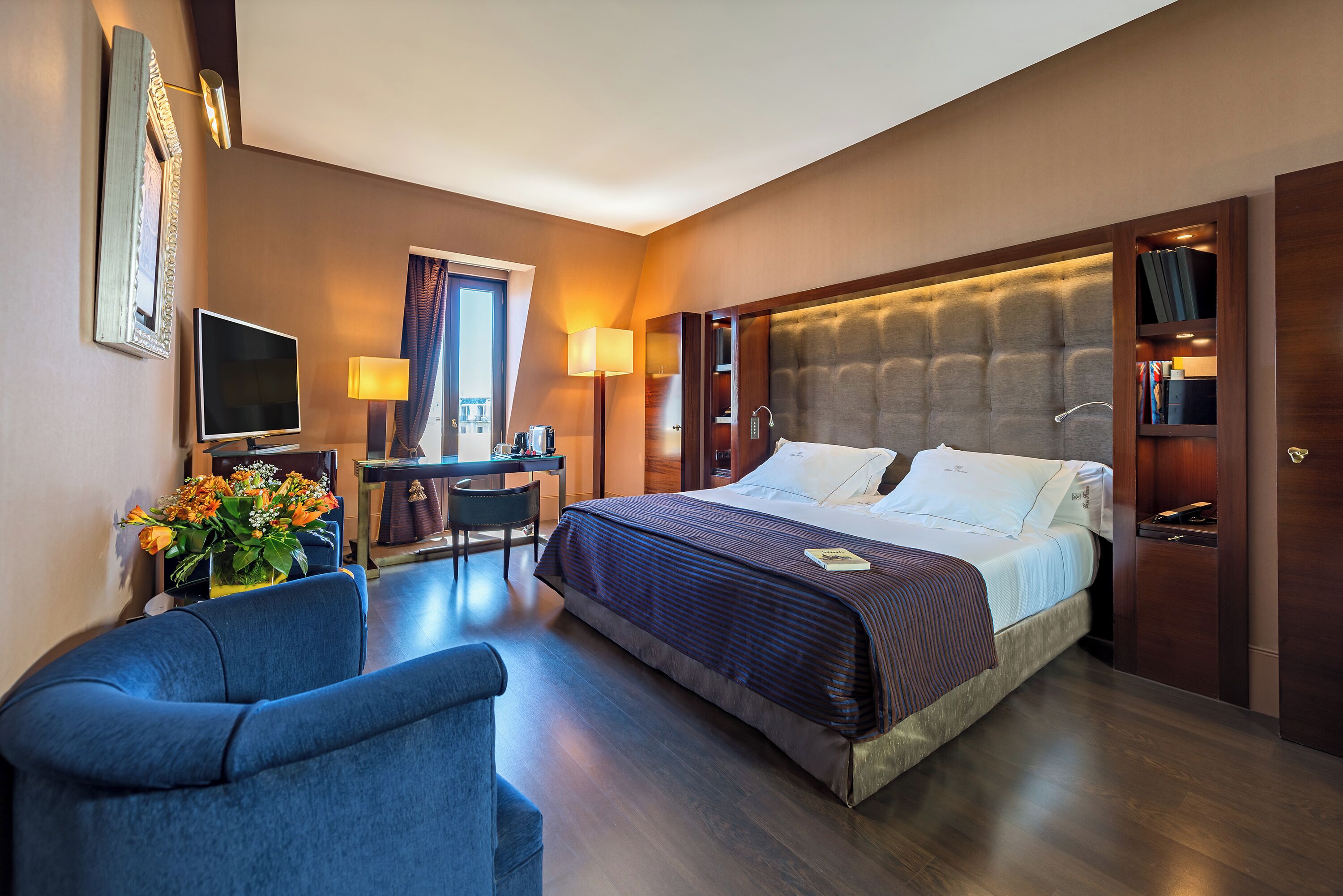 Een hotelkamer met een groot bed, een bureau, een stoel en een televisie.