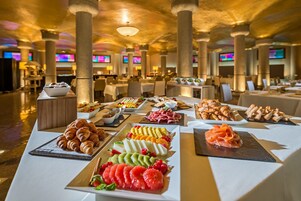 A buffet with various food items including pastries, fruits, and meats.