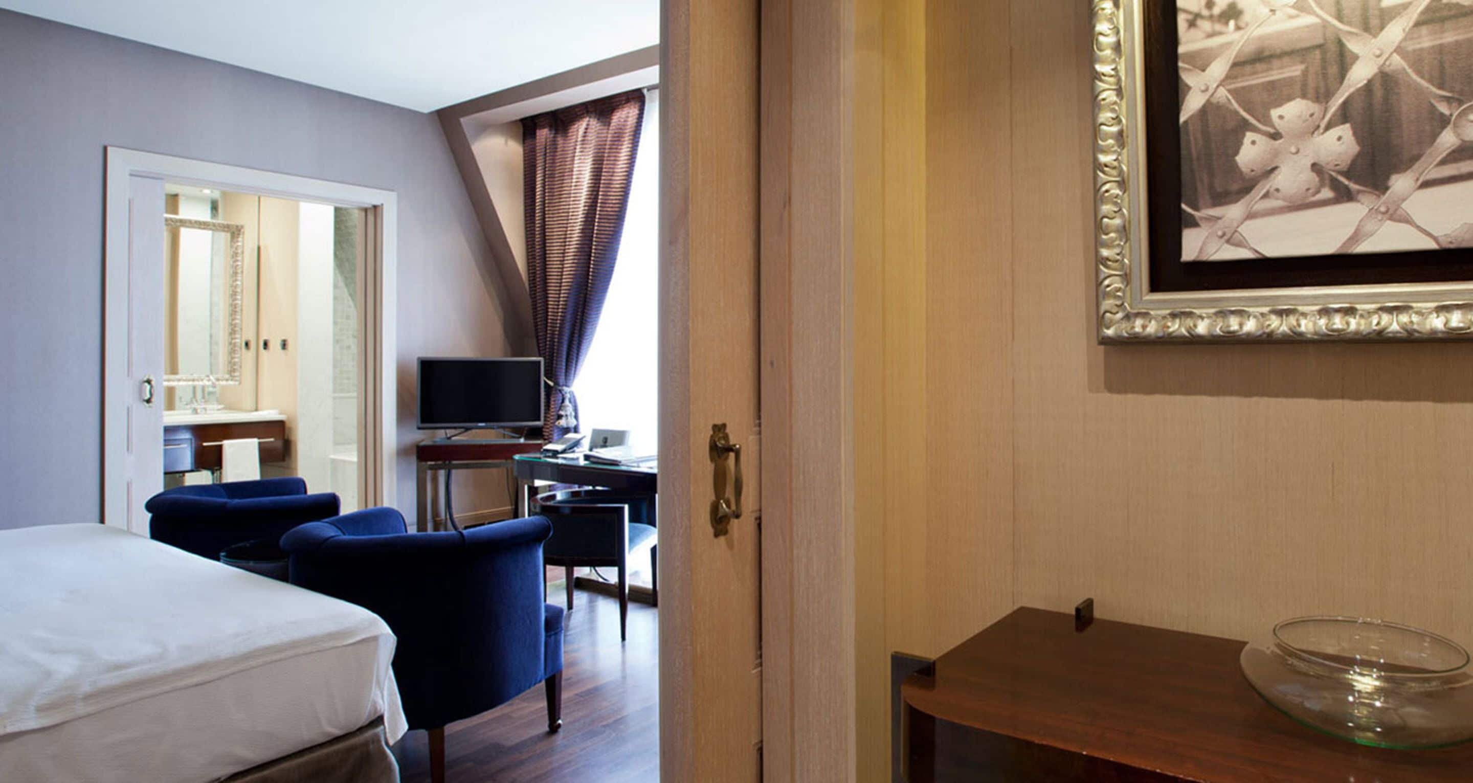 Habitación de hotel con cama, escritorio, computadora, silla y televisión.