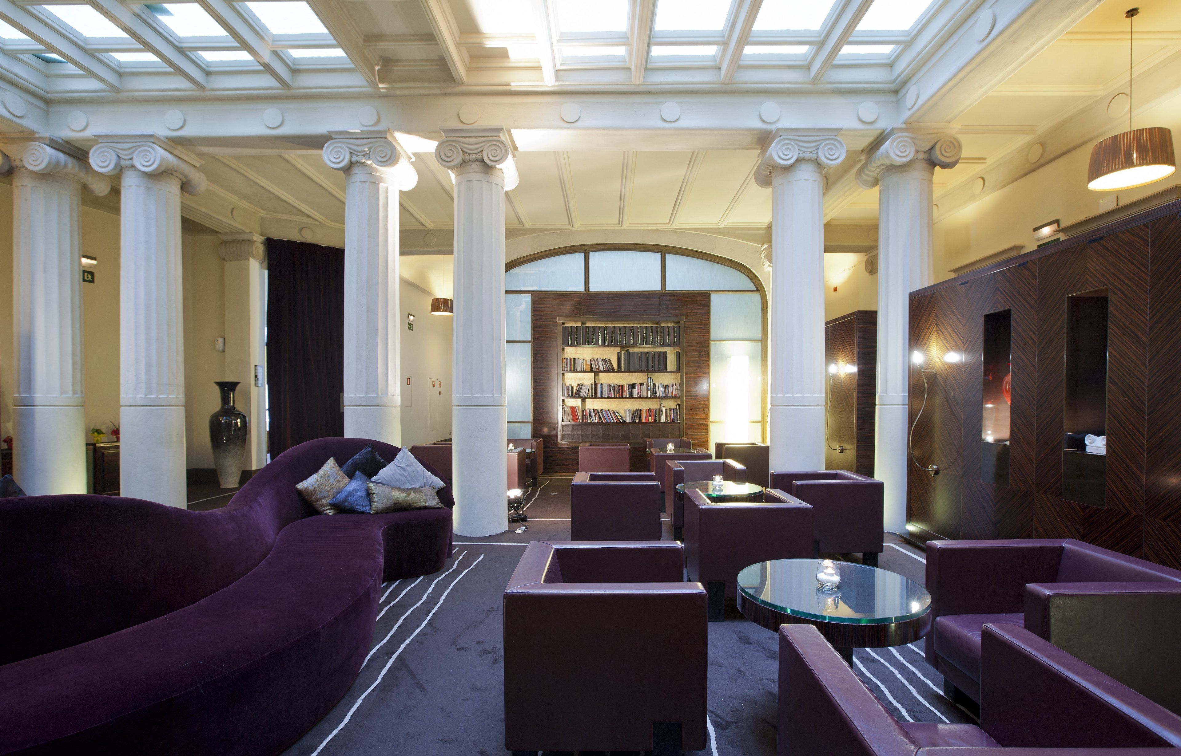 A spacious lobby with a central seating area, a large bookshelf, and a modern chandelier.