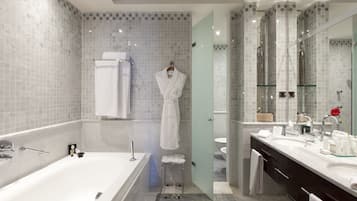 A modern bathroom with a large bathtub, a glass-enclosed shower, and a vanity with a mirror.
