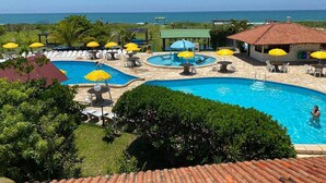 A pool area with multiple pools, sun loungers, and umbrellas. - Morro das Pedras Clube Hotel (Florianópolis)