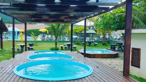 An outdoor pool area with multiple hot tubs and picnic tables. - Morro das Pedras Clube Hotel (Florianópolis)