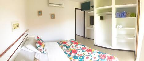 Un dormitorio con cama, un armario y un baño visible al fondo.