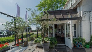 An outdoor seating area with tables and chairs, potted plants, and a covered patio.