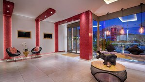 A modern lobby with red accents, seating areas, and a large window offering a view of the cityscape. - Raganelli Hotel (Rome)