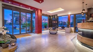 A modern lobby with large glass doors, a reception desk, and a seating area with a round table and chairs. - Raganelli Hotel (Rome)
