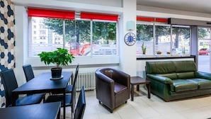 Una habitación moderna con una mesa de comedor, sillas, un sofá, una planta en maceta y un reloj en la pared.