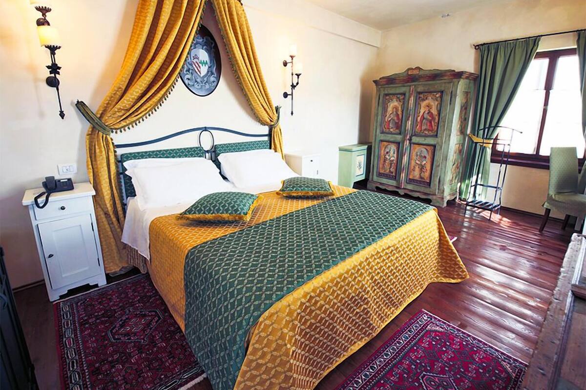 A room with a bed, a nightstand, a wardrobe, and a window with curtains.