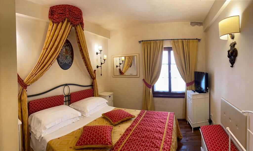 Un dormitorio con cama, cortinas, televisor y espejo.