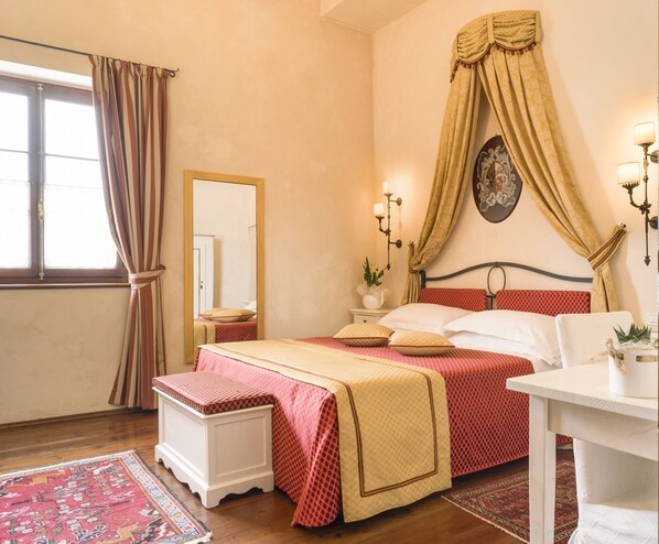 Un dormitorio con cama, mesitas de noche, un espejo y una ventana con cortinas.