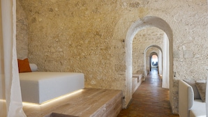 A modern room with a stone wall, a wooden staircase, and a bed with a white headboard.