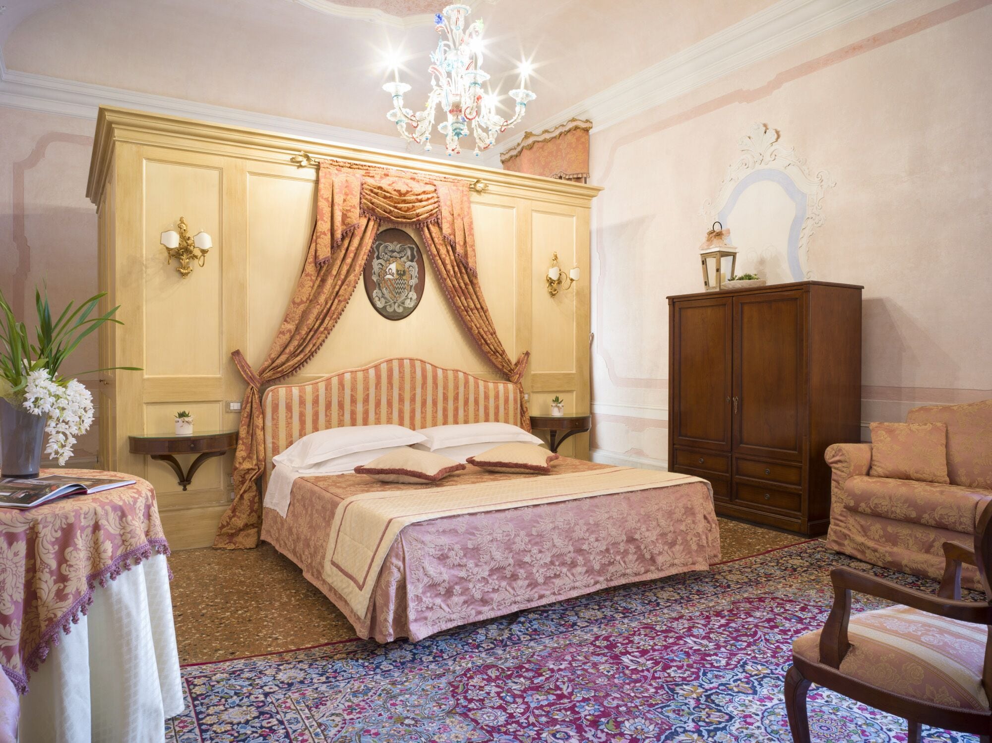 Una camera da letto con un letto grande, un'armadio in legno, un lampadario e un tappeto floreale.
