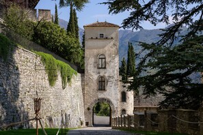 A stone tower with a tiled roof, arched entrance, and a rope barrier in front. - Castelbrando (Cison di Valmarino)