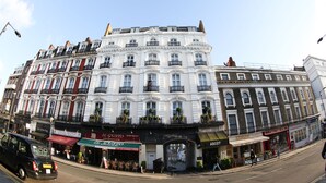 Une rangée d’immeubles à étages, abritant divers commerces au rez-de-chaussée, notamment un restaurant et un bar.