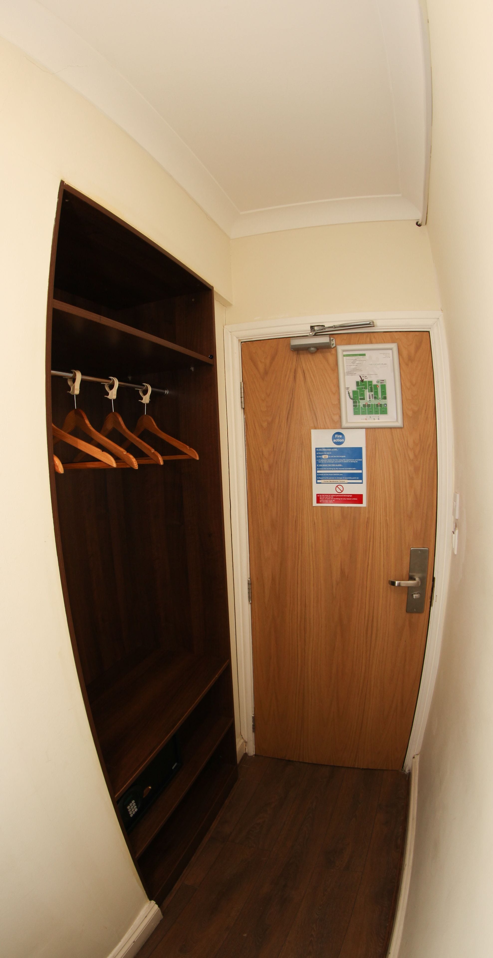 A narrow hallway with a wooden closet and a door with a sign.