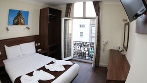 Une chambre d’hôtel avec un lit, une armoire, une salle de bain avec un miroir et un téléviseur fixé au mur.