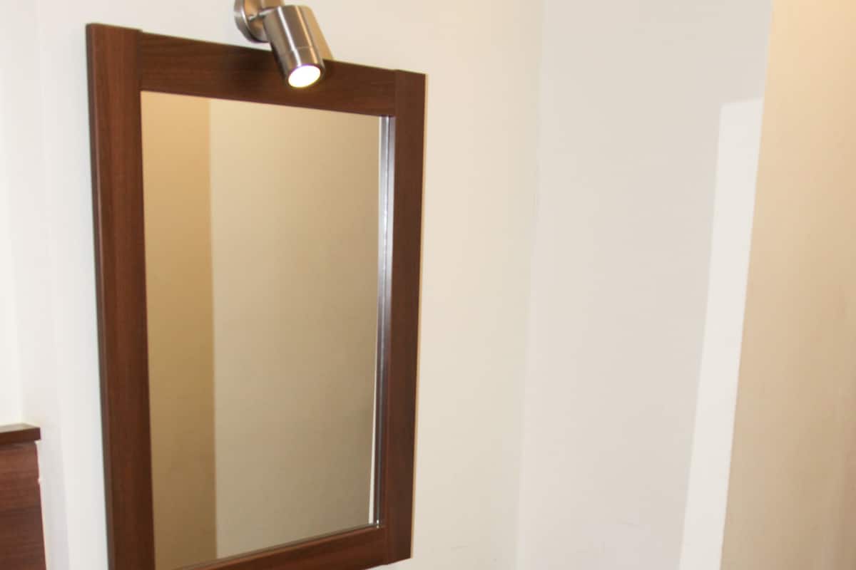 Een houten wastafel met spiegel, een lade en een bankje.