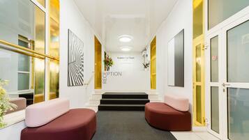 A reception area with a staircase leading to a second floor, a reception desk, and two seating areas with cushions.