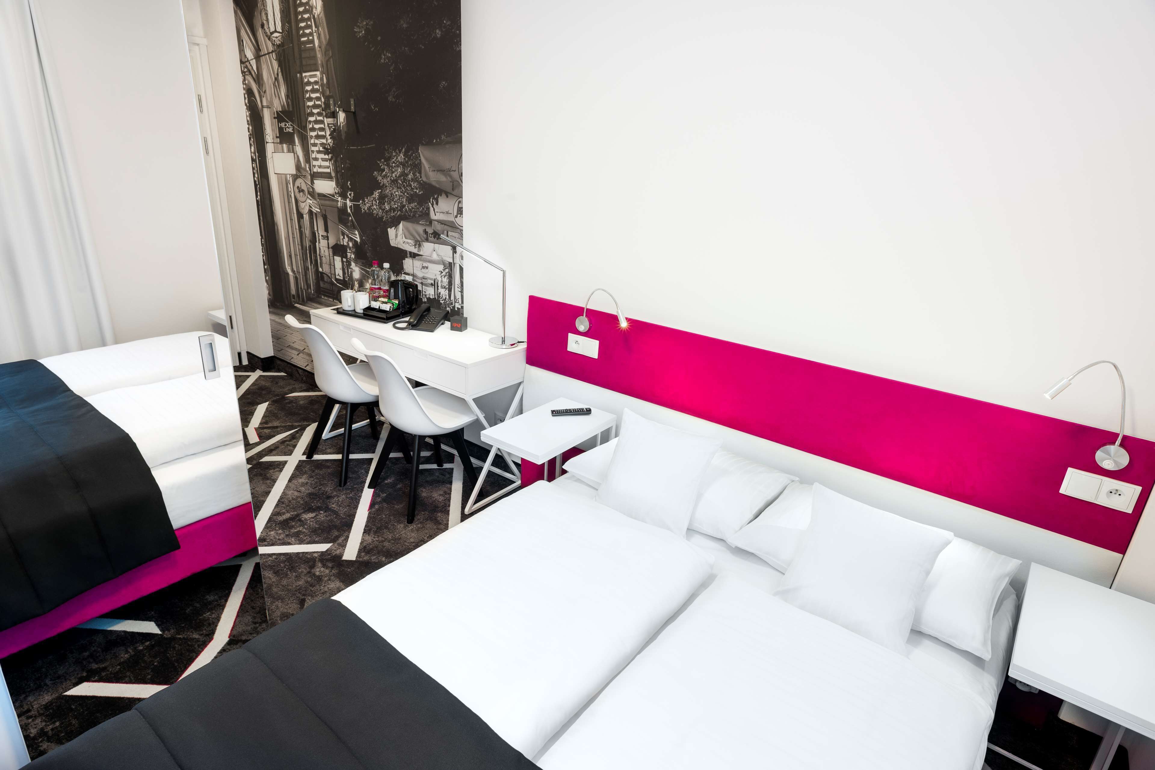 Habitación de hotel con dos camas, un escritorio, una silla y un mural grande en la pared.