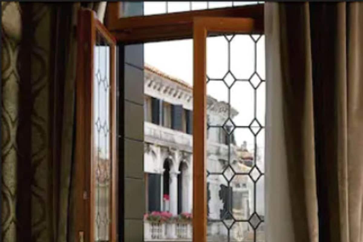 Una habitación con un conjunto de sofá, una mesita con una revista y vistas a través de una ventana con celosía metálica.