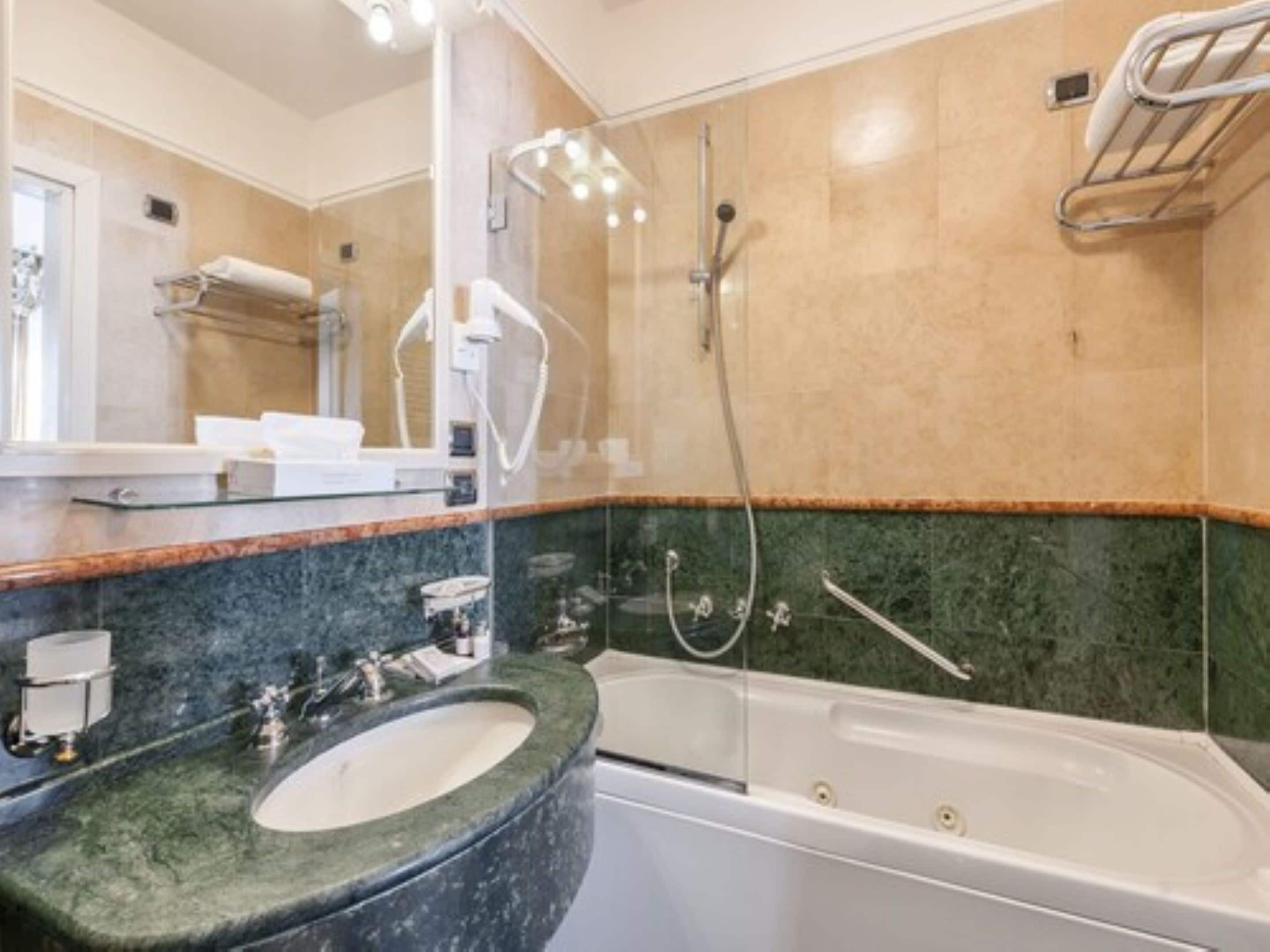 Un baño moderno con una bañera grande, un lavamanos independiente y una zona de ducha con mampara de vidrio.