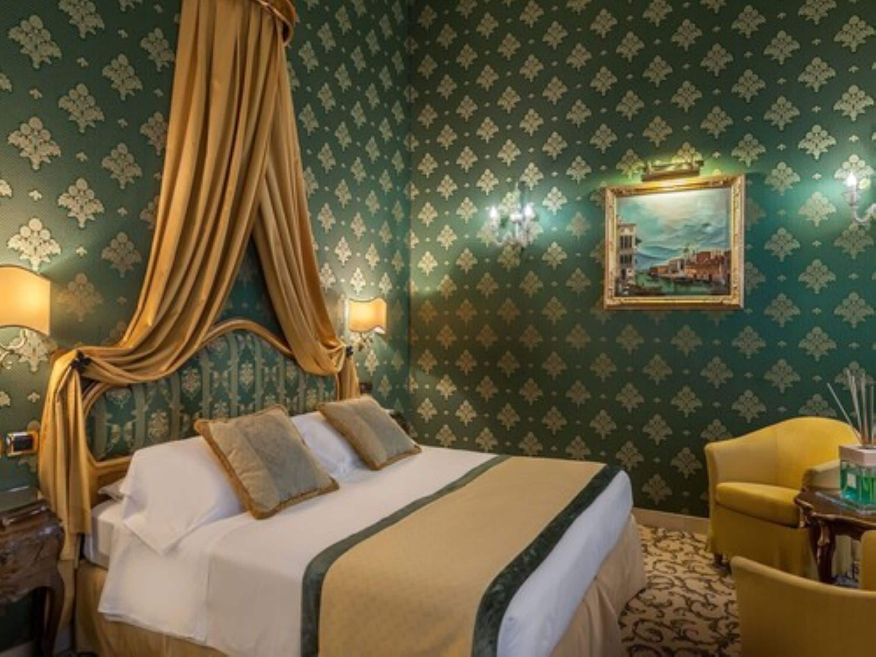 A four-poster bed with a canopy, a painting on the wall, and a chair with a table beside the bed.