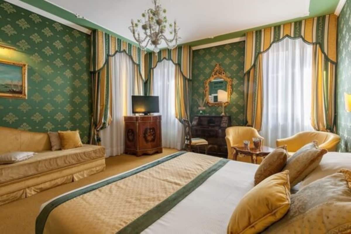 Una habitación de hotel con cama, sofá, televisor, cómoda y una silla.
