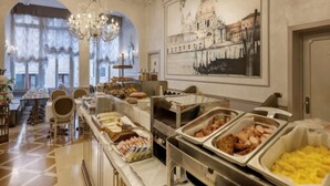 A buffet area with various food options, a chandelier, and a large framed picture of a building. - Ca' Dei Conti (Venice)