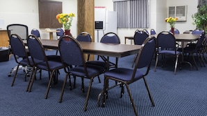 Un salón de conferencias con una gran mesa, varias sillas y dos jarrones con flores.