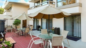 Un edificio moderno con un patio que ofrece mobiliario exterior y sombrillas.