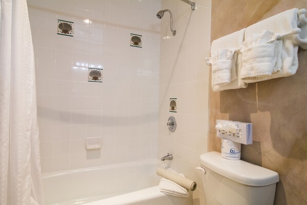 A bathroom with a bathtub, toilet, and towel rack. - Colton Inn (Monterey)